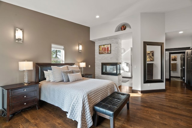 bedroom with dark wood-style floors, baseboards, a multi sided fireplace, and recessed lighting