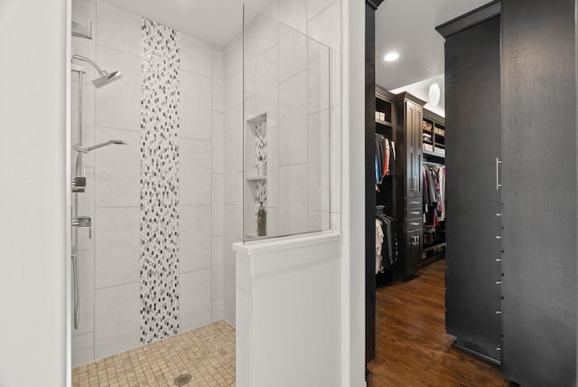 bathroom featuring tiled shower, a spacious closet, and wood finished floors