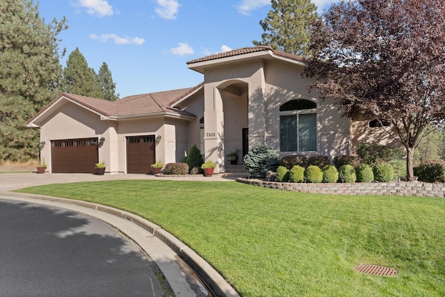 mediterranean / spanish house with a garage, stucco siding, a tiled roof, and a front yard