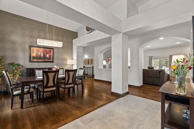 dining space featuring arched walkways, french doors, wood finished floors, and baseboards