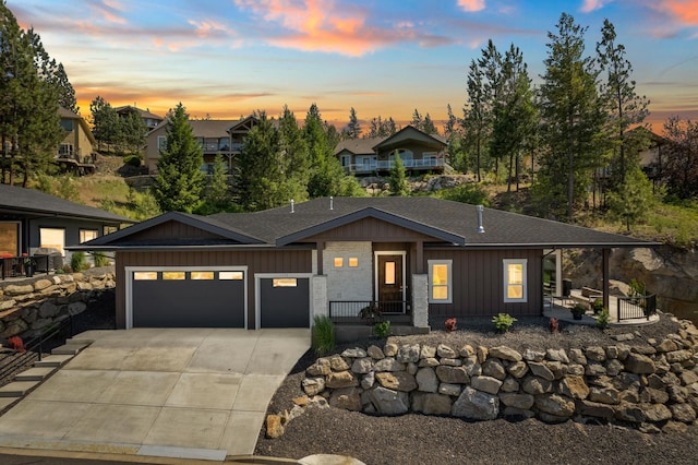 view of front of home featuring a garage, covered porch, driveway, roof with shingles, and board and batten siding