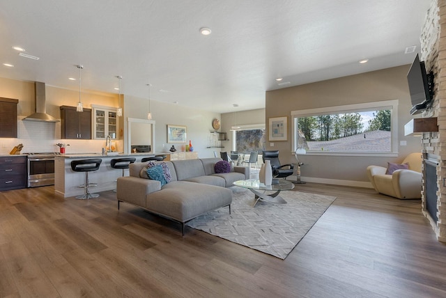 living area with recessed lighting, baseboards, wood finished floors, and a stone fireplace