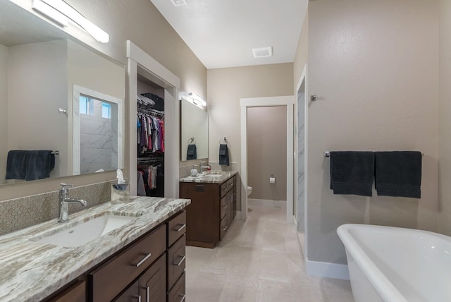 full bathroom with a freestanding bath, two vanities, a sink, and visible vents