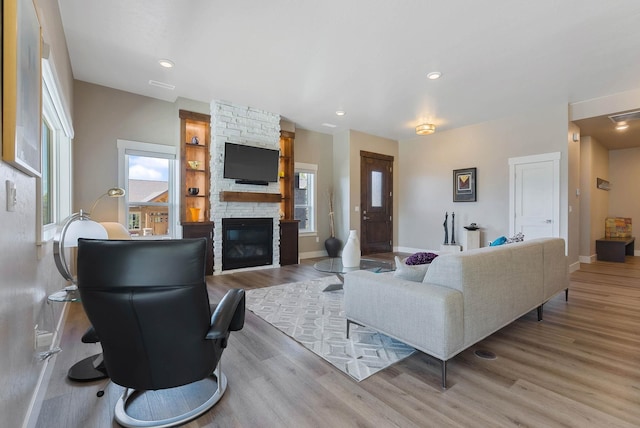 living area featuring recessed lighting, a fireplace, wood finished floors, visible vents, and baseboards