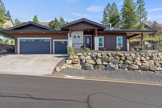 view of front facade featuring an attached garage, stone siding, board and batten siding, and concrete driveway