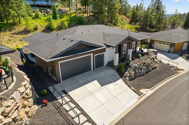 view of front of house featuring roof with shingles, driveway, and an attached garage