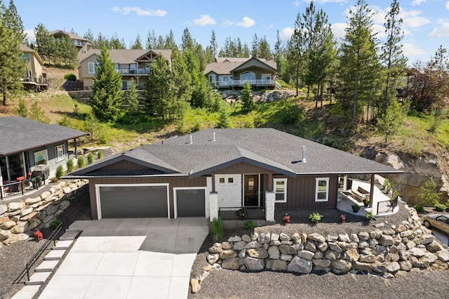 view of front facade with a garage, a residential view, concrete driveway, and a shingled roof