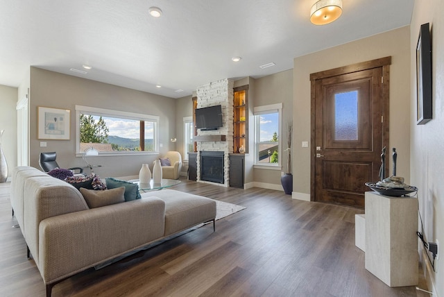 living area with a wealth of natural light, a fireplace, baseboards, and wood finished floors