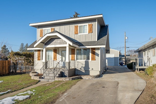 view of front of home with a detached garage, fence, an outdoor structure, a porch, and board and batten siding