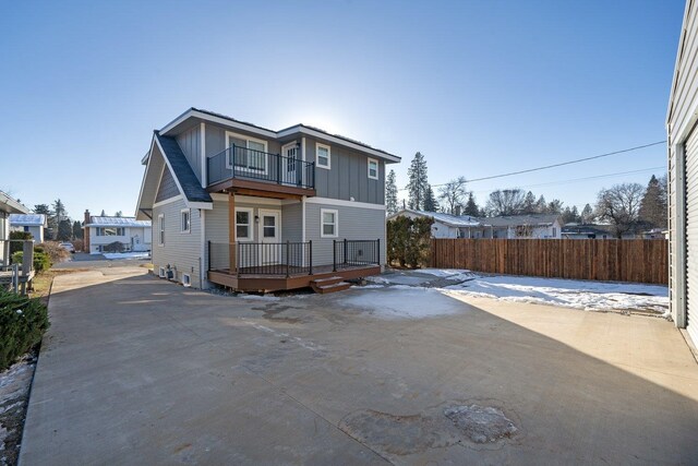 view of front of house featuring board and batten siding, fence, and a balcony