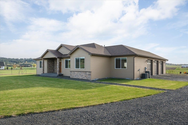 view of front of home featuring central air condition unit, a front yard, a garage, stone siding, and driveway