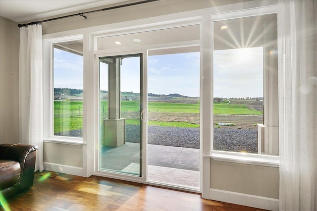 doorway featuring baseboards, wood finished floors, and a rural view