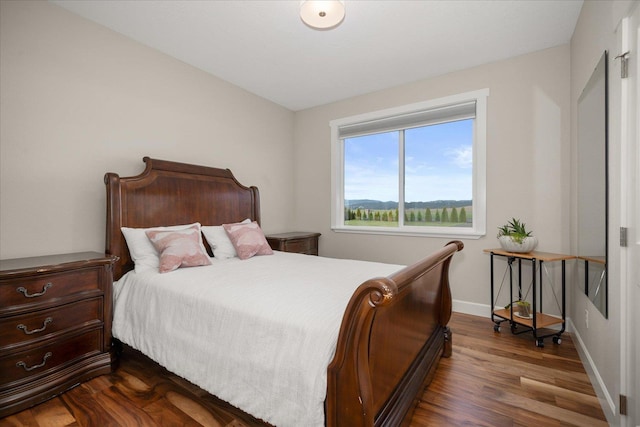 bedroom with dark wood-type flooring and baseboards