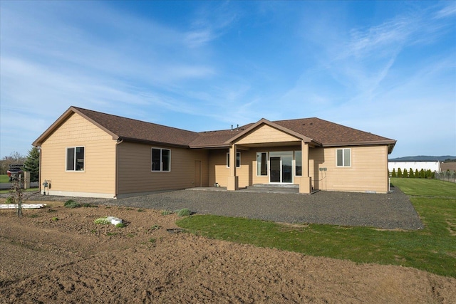 back of property featuring roof with shingles and a yard