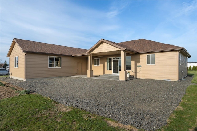 back of house with a patio and roof with shingles