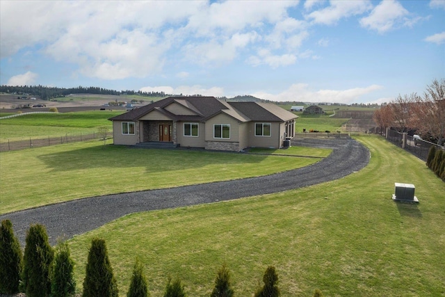 view of front of home featuring fence, a front lawn, and a rural view