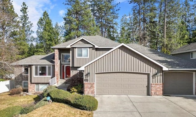 split level home with a garage, brick siding, driveway, and roof with shingles