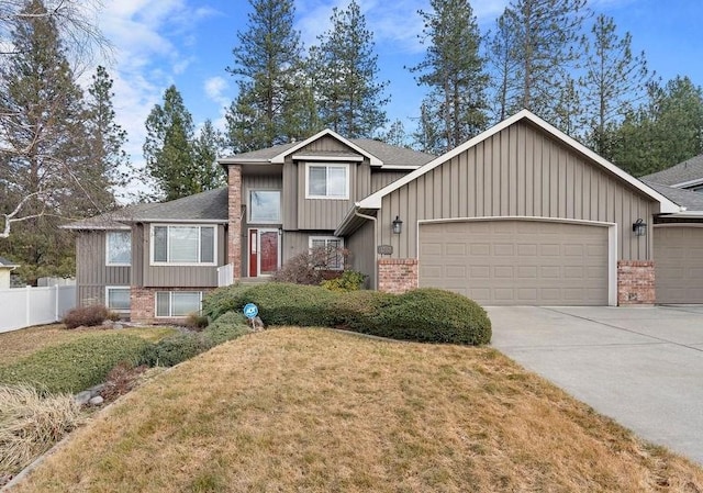 view of front facade with a garage, brick siding, fence, driveway, and a front yard