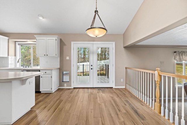 kitchen featuring light countertops, tasteful backsplash, white cabinets, and light wood-style floors