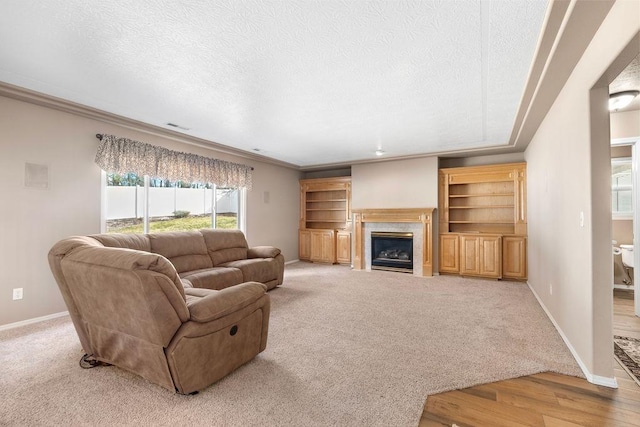 carpeted living room with a textured ceiling, a premium fireplace, visible vents, and baseboards