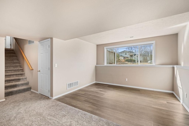 basement with stairway, baseboards, visible vents, and wood finished floors