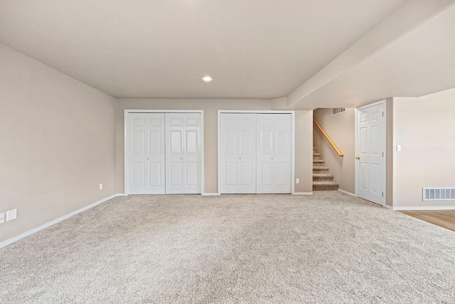 unfurnished bedroom with baseboards, carpet, visible vents, and multiple closets