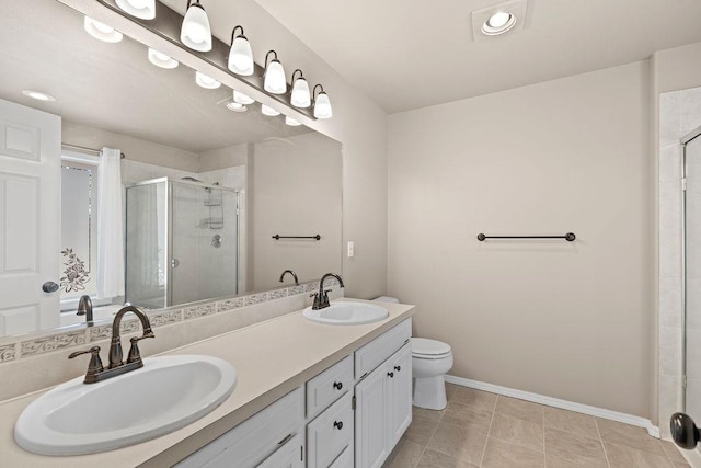 bathroom featuring double vanity, a shower stall, baseboards, and a sink