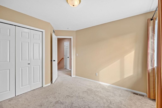 unfurnished bedroom with carpet floors, a closet, visible vents, and baseboards