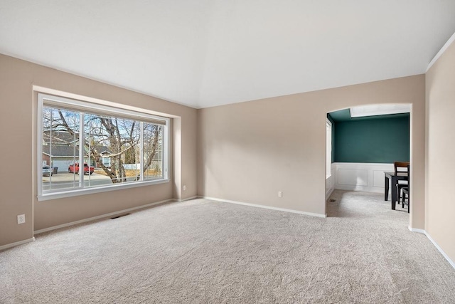 empty room featuring vaulted ceiling, carpet, visible vents, and baseboards