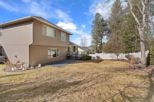 rear view of property featuring a patio, a lawn, fence, and a wooden deck