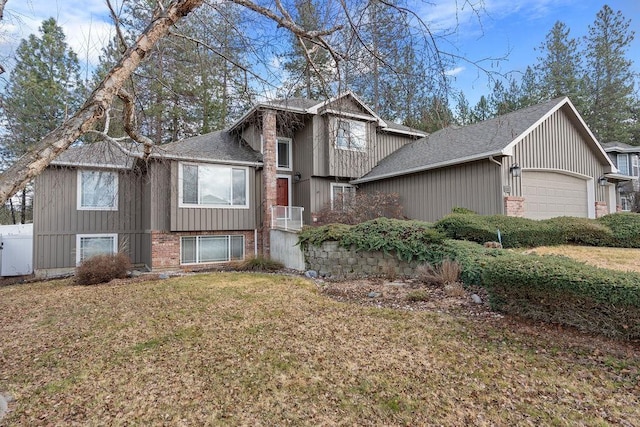 tri-level home featuring a garage, a shingled roof, a front lawn, and brick siding