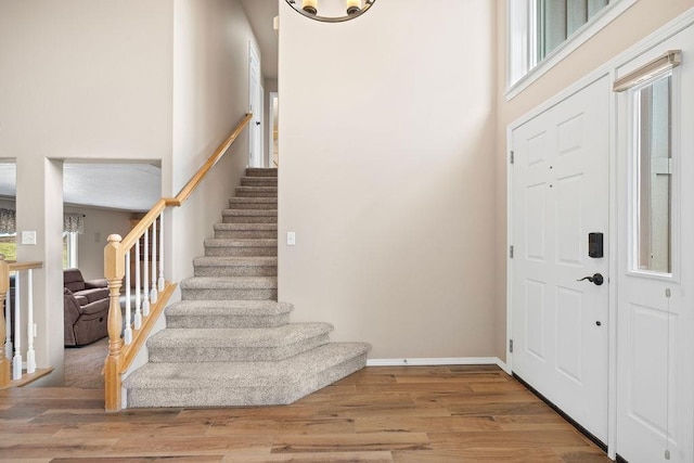 entrance foyer with baseboards, stairway, a high ceiling, and wood finished floors