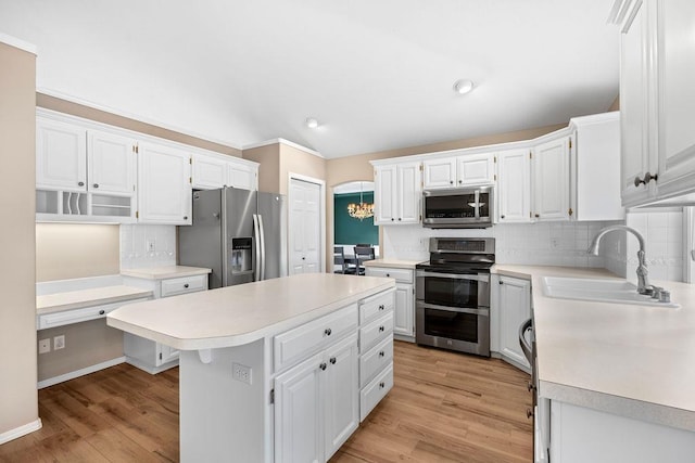 kitchen with light countertops, appliances with stainless steel finishes, a kitchen island, and a sink