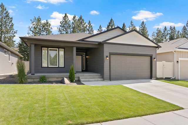 view of front of home featuring roof with shingles, concrete driveway, a front yard, fence, and a garage