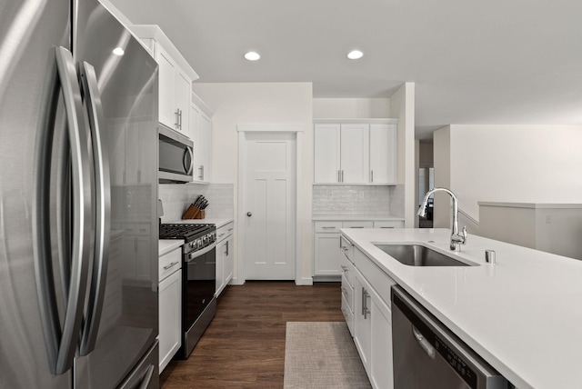 kitchen with stainless steel appliances, a sink, white cabinetry, light countertops, and dark wood-style floors