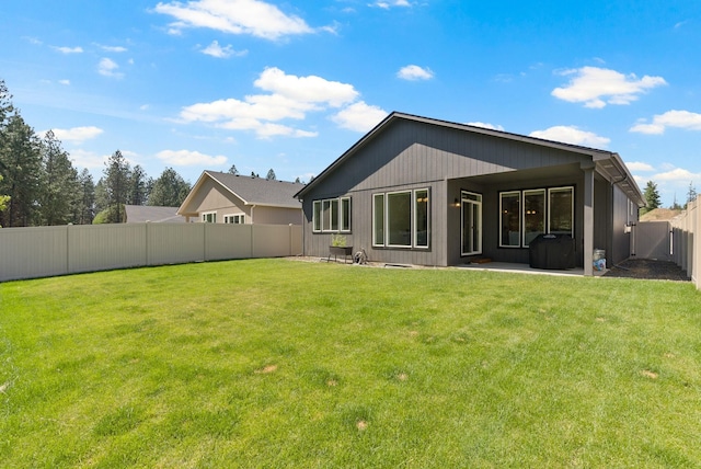 rear view of property featuring a yard, a patio area, and a fenced backyard