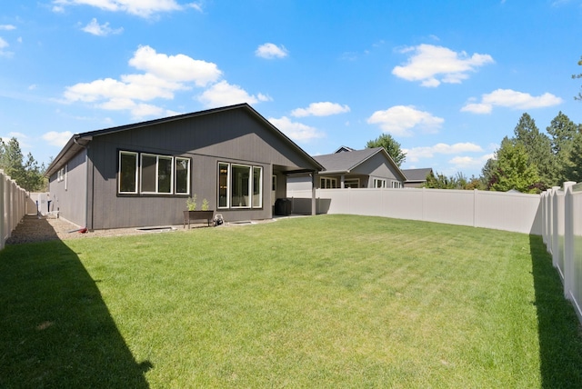 rear view of property with a yard and a fenced backyard