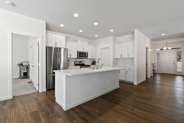 kitchen featuring stainless steel appliances, light countertops, a center island with sink, and white cabinets