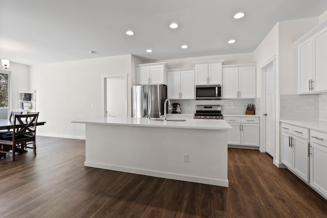 kitchen featuring stainless steel appliances, dark wood-type flooring, an island with sink, and a sink