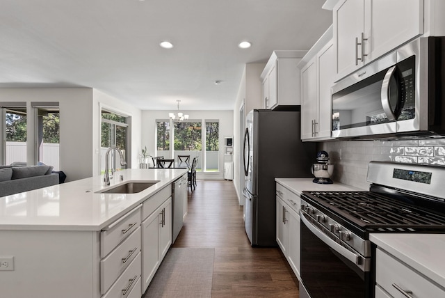 kitchen with dark wood-style flooring, tasteful backsplash, light countertops, appliances with stainless steel finishes, and a sink