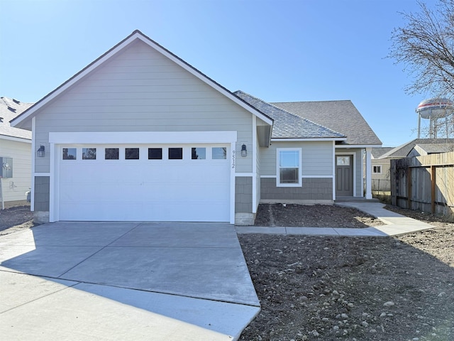 ranch-style house featuring concrete driveway, a shingled roof, an attached garage, and fence