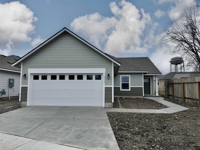 ranch-style house with a shingled roof, an attached garage, concrete driveway, and fence