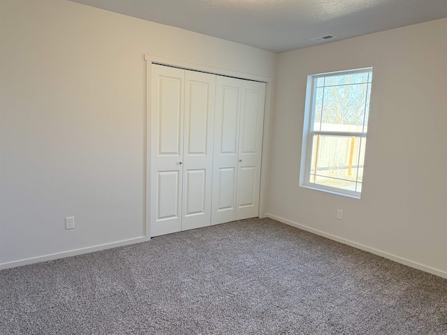 unfurnished bedroom featuring carpet floors, baseboards, visible vents, and a closet