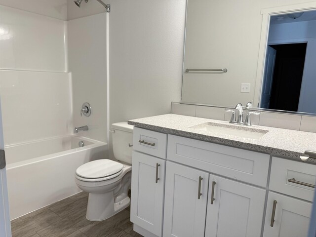 bathroom with shower / bathing tub combination, vanity, toilet, and wood finished floors