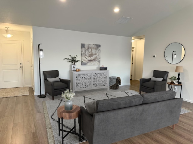 living area featuring baseboards, visible vents, and wood finished floors