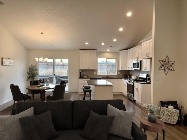 kitchen with stainless steel appliances, a center island, open floor plan, decorative backsplash, and an inviting chandelier