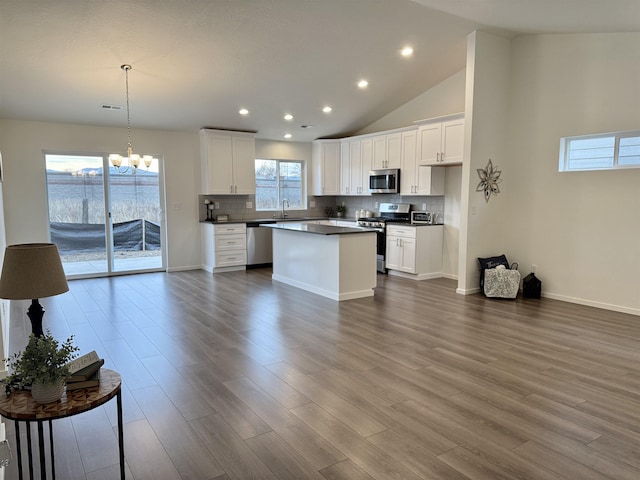 kitchen featuring stainless steel appliances, dark wood-type flooring, dark countertops, and backsplash