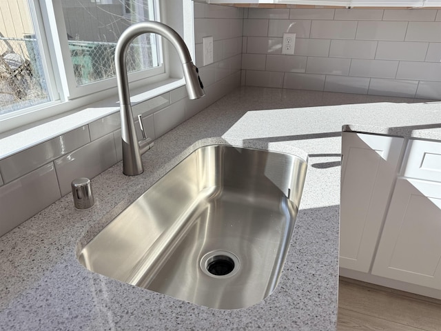 interior details with light stone counters, a sink, and backsplash