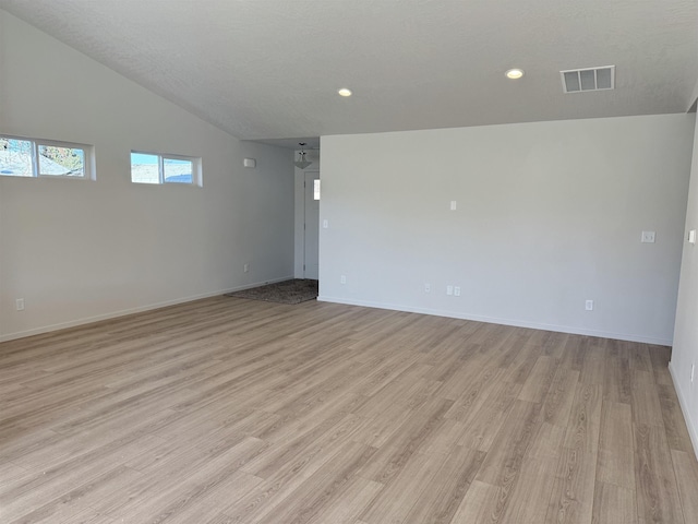 unfurnished room featuring baseboards, visible vents, vaulted ceiling, light wood-style floors, and recessed lighting