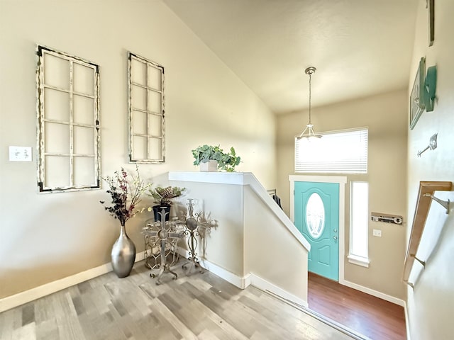 foyer with high vaulted ceiling, baseboards, and wood finished floors